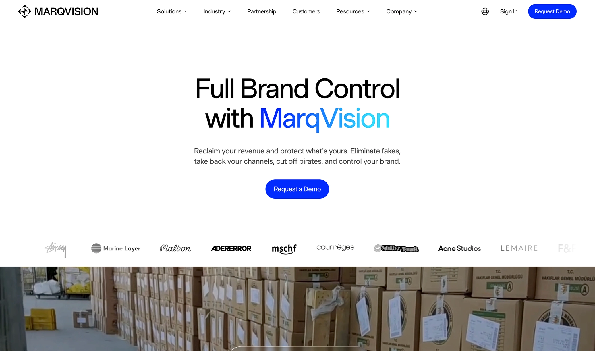 MarqVision homepage with headline 'Full Brand Control with MarqVision', a button to request a demo, and logos of partner brands above an image of stacked boxes in a warehouse.